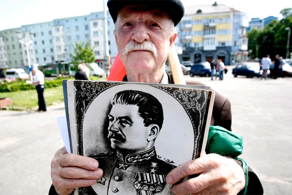 Участник митинга в Калининграде держит в руках портрет Иосифа Сталина.