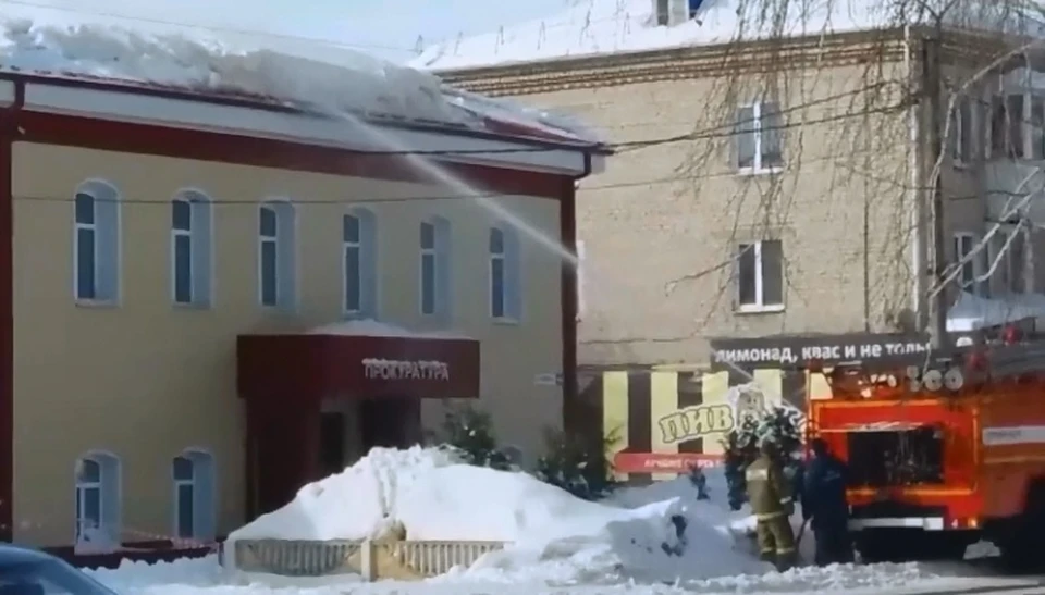 Кадр из видео: бригада пожарных поливает из брандспойта крышу здания прокуратуры.