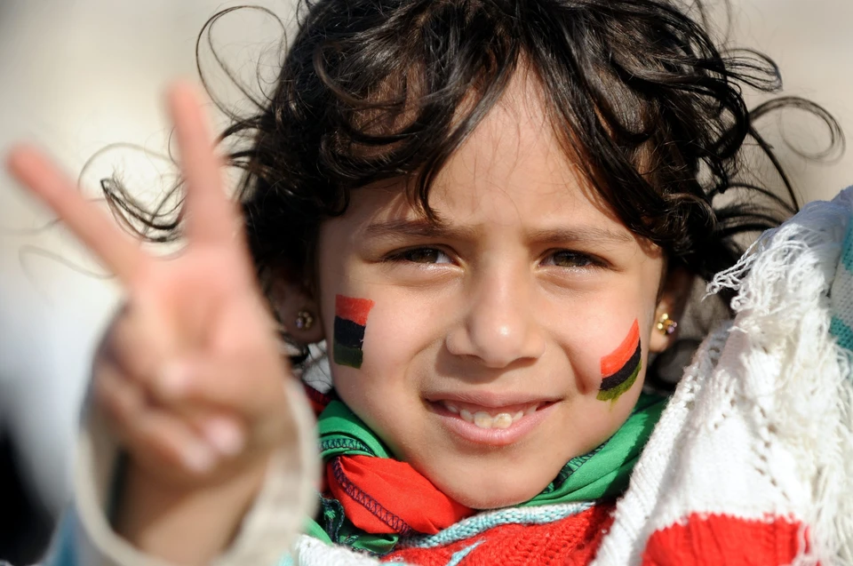 Бенгази, весна 2011 года. Девочка c флагами ливийской революции демонстрирует победный жест.