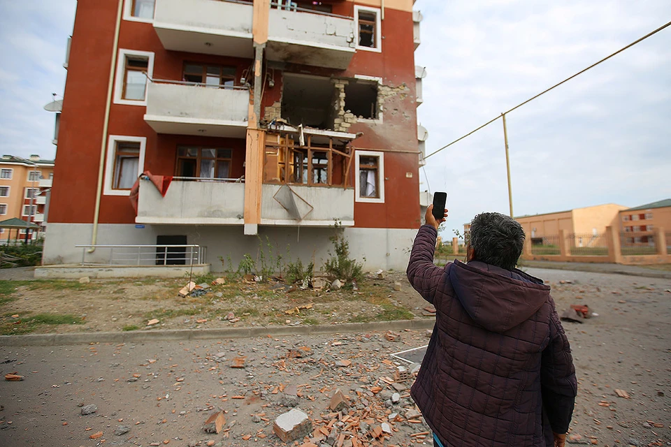 Мужчина фотографирует разрушения от обстрела в одном из сёл в районе боевых действий Карабахского конфликта.