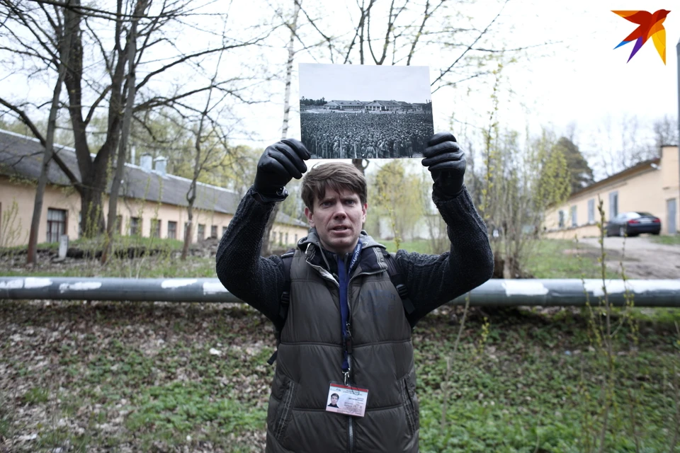 Экскурсовод Дмитрий Морозов на месте лагеря военнопленных Шталаг 352 показывает архивное фото 1940-х
