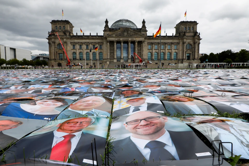 Тем временем у Рейхстага проходит акция протеста. Активисты выложили портретами политиков пространство у парламента.