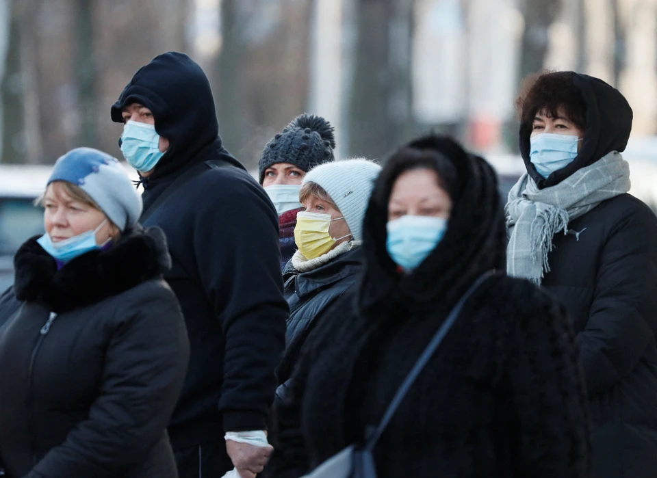 Киевляне в масках ждут автобуса на остановке общественного транспорта.