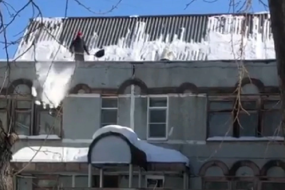 Воспитатели чистят крышу детского сада №26 в Комсомольске. Фото: скриншот с видео