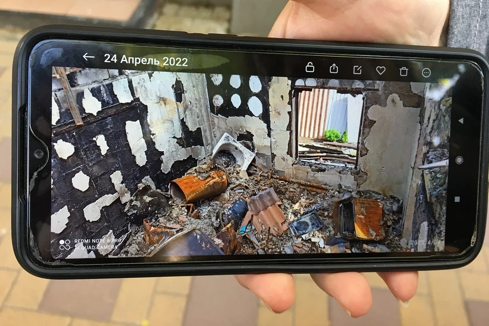 Беженка из Мариуполя на телефоне показывает разрушенный дом.