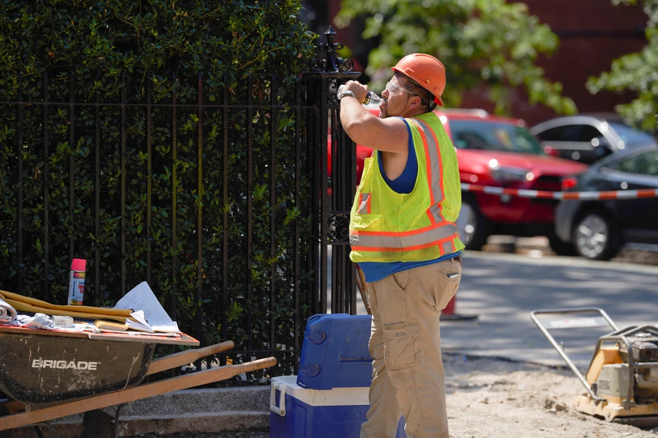 Доброжный рабочий пьет воду на улицах Бостона, США.