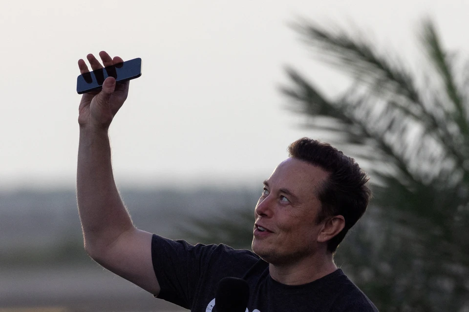 Маск поднимает телефон к небу на космической базе SpaceX в Браунсвилле, штат Техас.