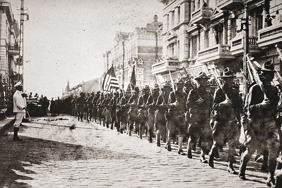 Август 1918 года, Владивосток. Американские войска маршируют перед зданием, занятым под штаб чехословаков. Японцы в почетном карауле. Фото: wikipedia.org