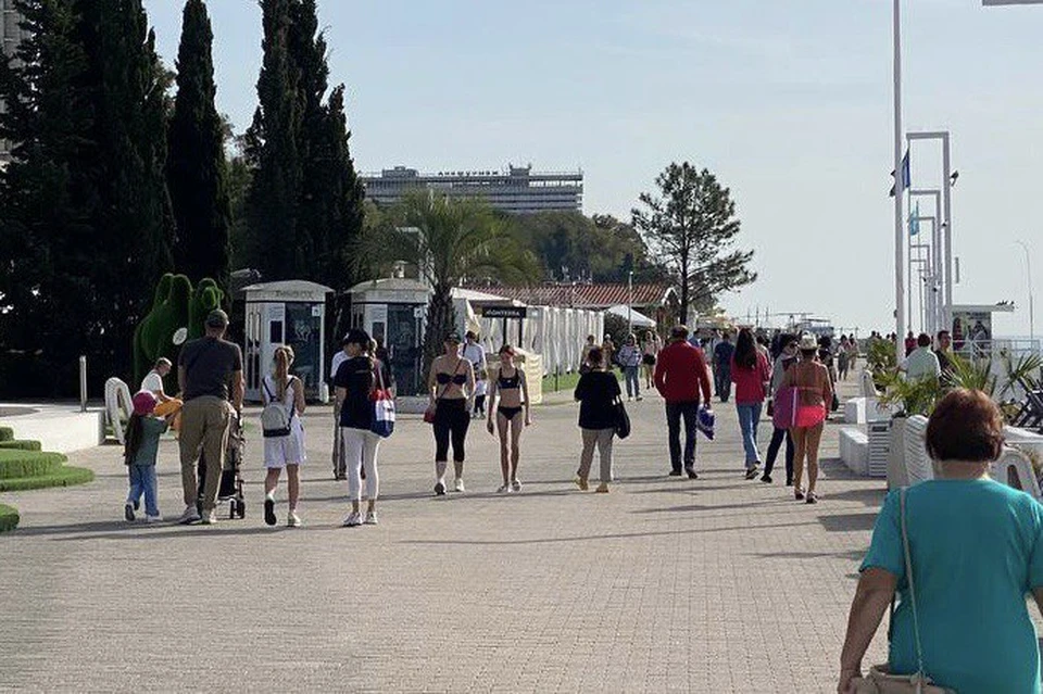 Туристы гуляют по набережной Сочи в купальниках