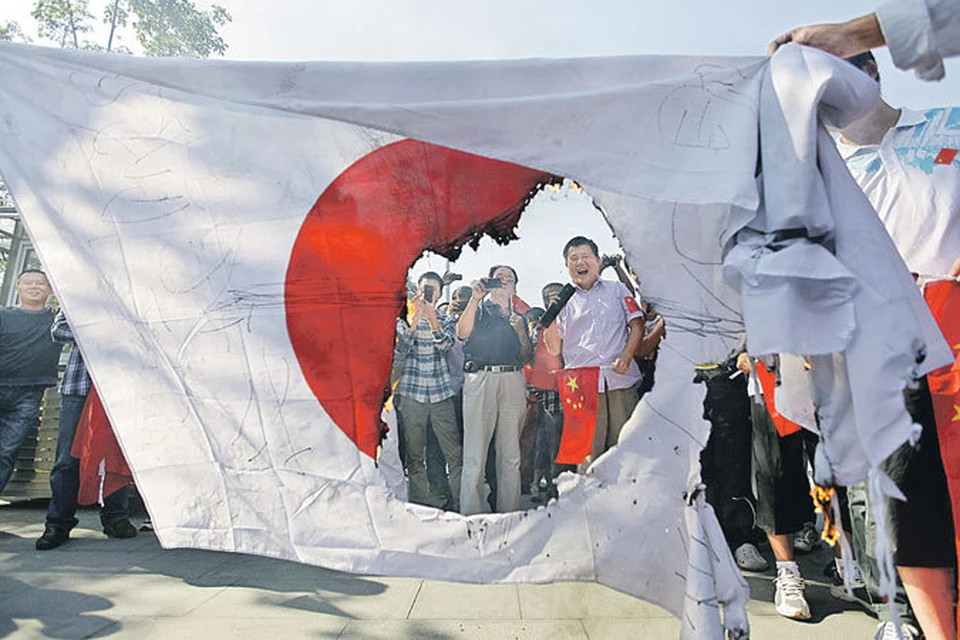 Китайские демонстранты жгут национальный флаг Японии.