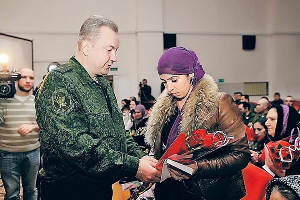 Заместитель командующего Внутренними войсками МВД генерал-лейтенант Валерий Новожилов вручает цветы и деньги вдове погибшего солдата Раисе Решидовой