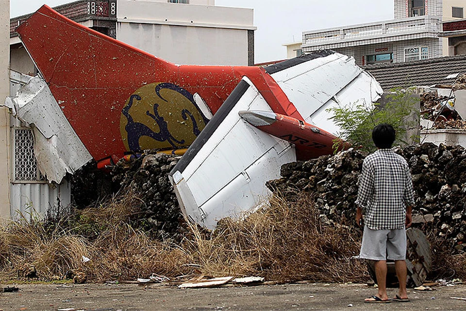 Мужчина осматривает место крушение самолета авиакомпании TransАsia на Тайване